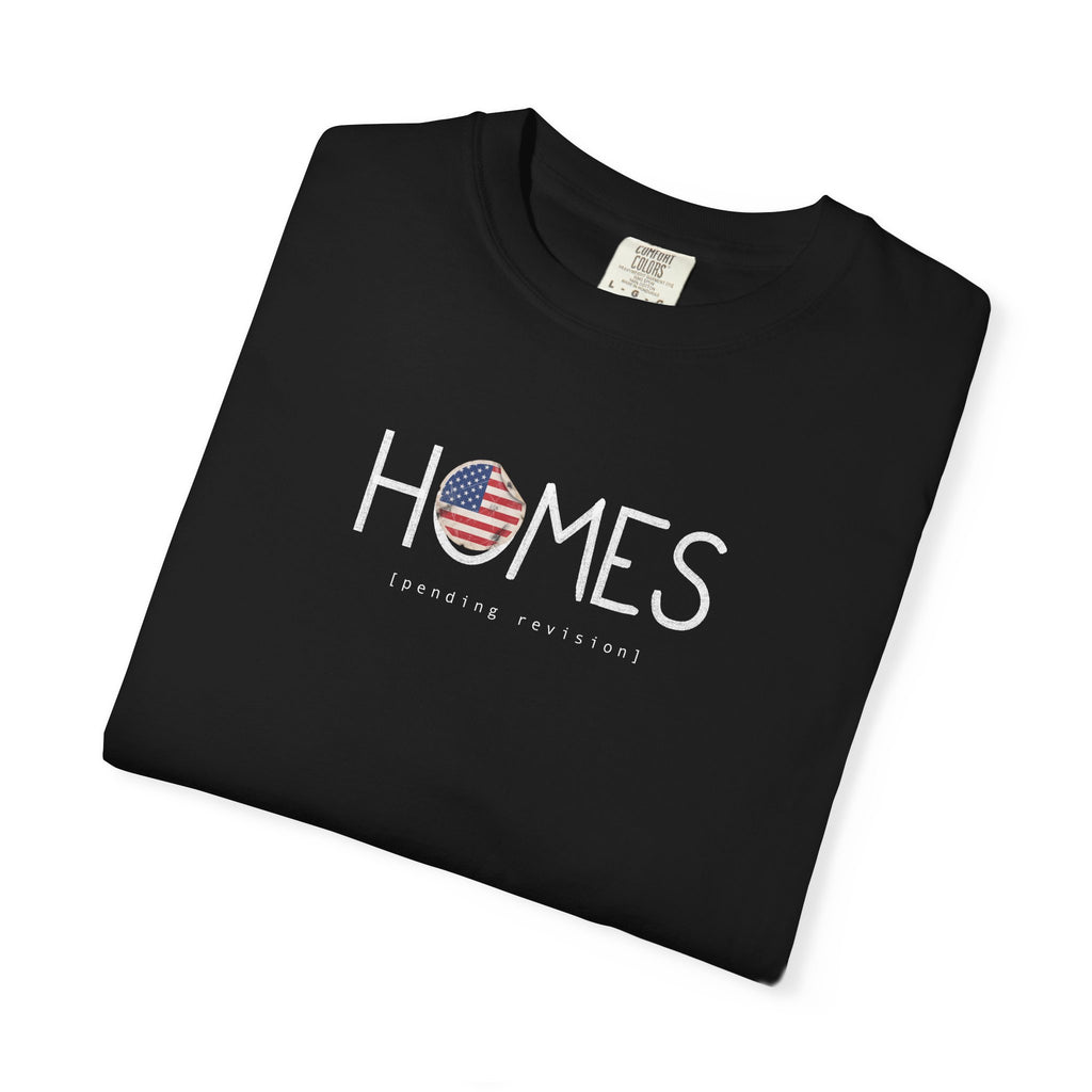 Black Course America tee, folded, showing HOMES in white with a flag filled O, above the words pending revision